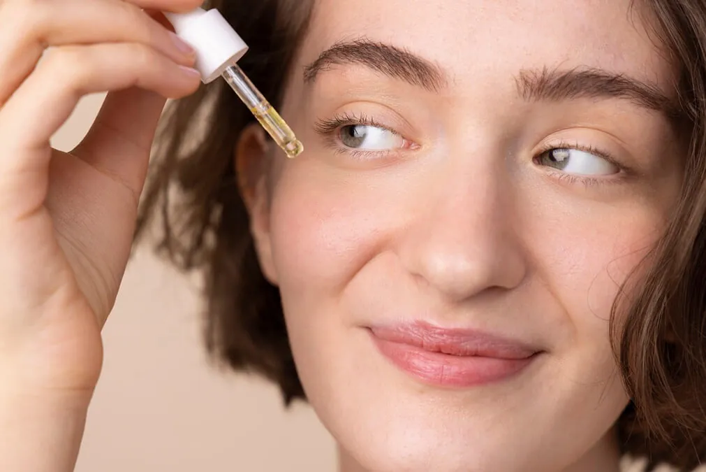 close up smiley girl using face serum 1