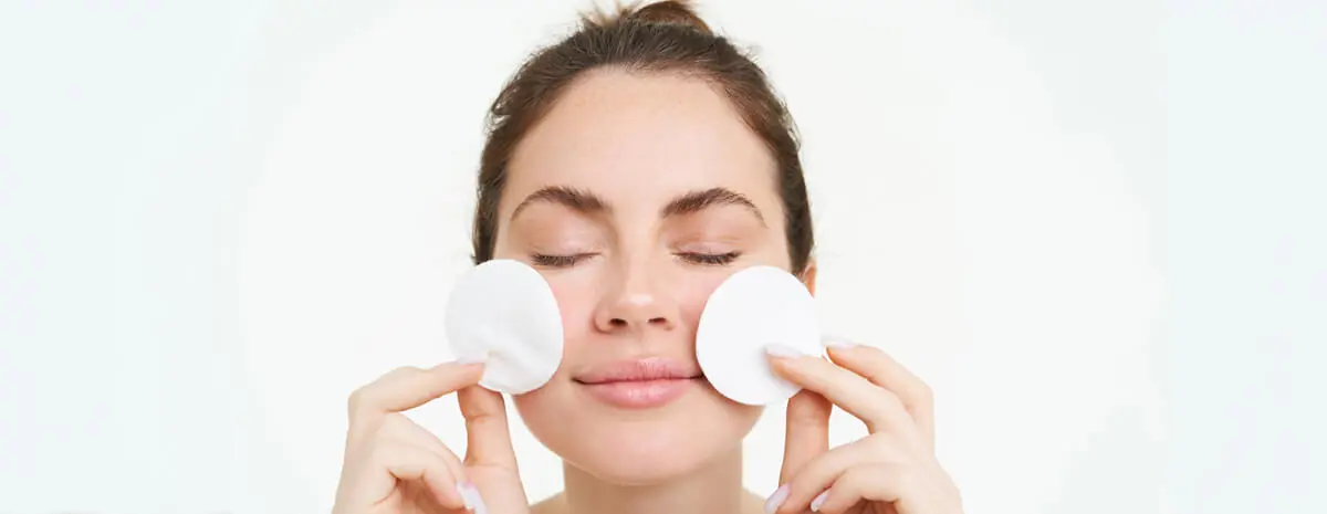image young woman taking off her makeup with cotton pads using facial cleanser cleaning her face 1