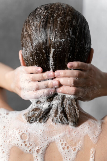 young woman applying anti dandruff product 1